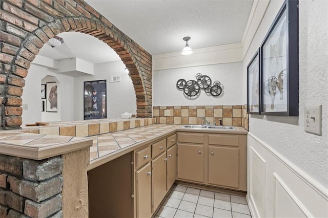 1803 N Jeter Rd, Raymore, MO 64083 - kitchen with tile counters, light tile patterned floors, arched walkways, a textured ceiling, and a textured wall