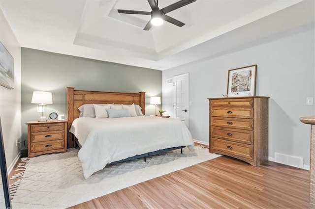 1803 N Jeter Rd, Raymore, MO 64083 - bedroom featuring a tray ceiling, light wood-style flooring, and ceiling fan