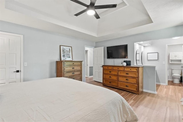 1803 N Jeter Rd, Raymore, MO 64083 - bedroom featuring a raised ceiling, light wood-style flooring, ensuite bathroom, and a ceiling fan