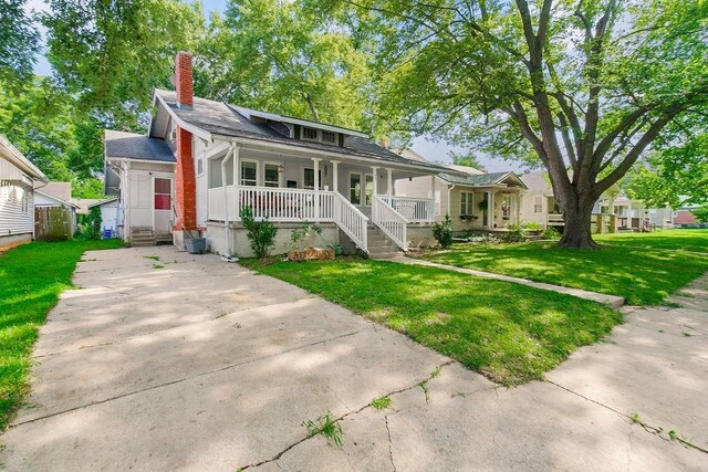 327 Parker Ave, Osawatomie, KS 66064 - bungalow with a porch, a chimney, a front lawn, and concrete driveway