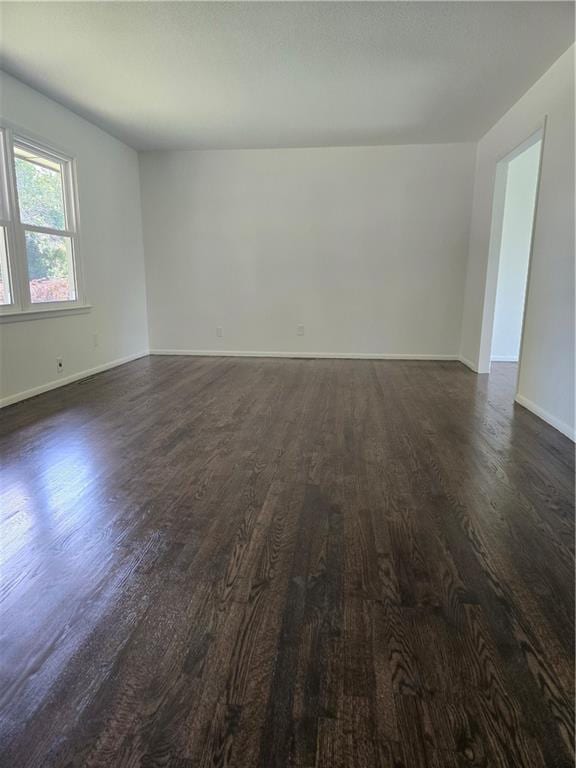 6302 E 120th Ter, Grandview, MO 64030 - spare room featuring dark wood-style flooring and baseboards
