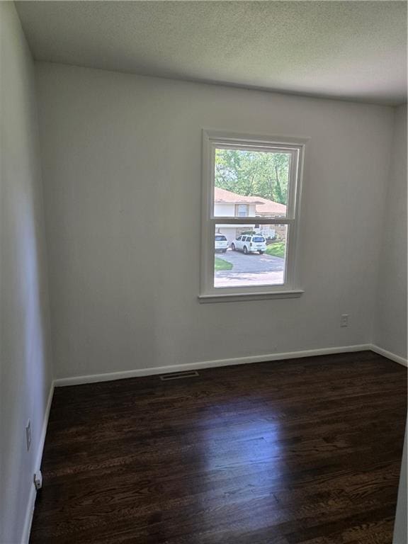 6302 E 120th Ter, Grandview, MO 64030 - empty room with dark wood-style flooring and a textured ceiling