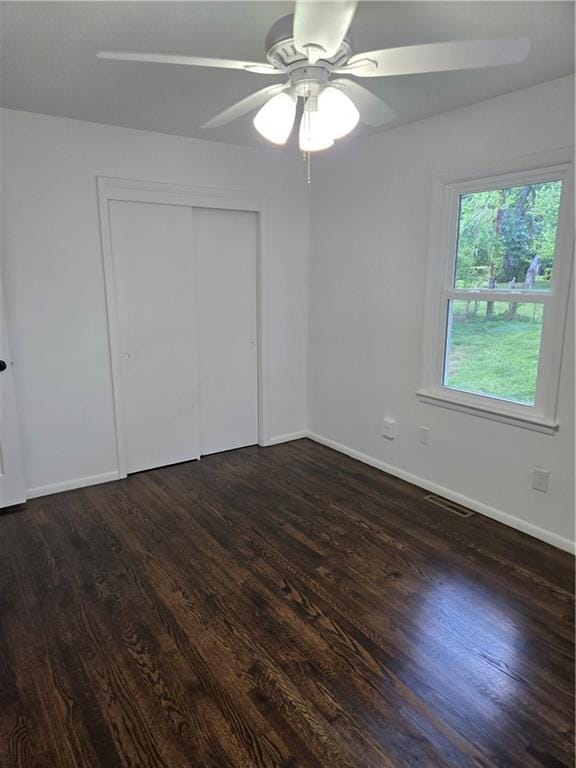 6302 E 120th Ter, Grandview, MO 64030 - unfurnished bedroom featuring dark wood finished floors, a closet, and a ceiling fan