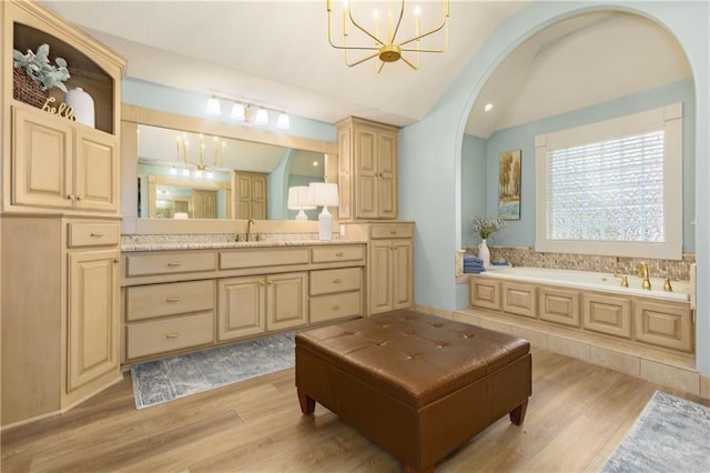 9445 W 157th Pl, Overland Park, KS 66221 - bathroom with a chandelier, lofted ceiling, wood finished floors, a garden tub, and vanity