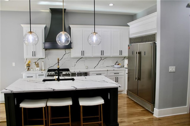 5443 N 101st Ter, Kansas City, KS 66109 - kitchen featuring stainless steel built in refrigerator, range hood, a breakfast bar, light wood finished floors, and backsplash