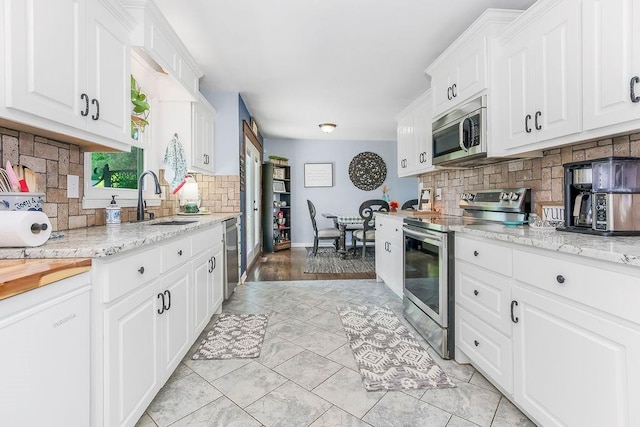3006 S 39th St, Kansas City, KS 66106 - kitchen with stainless steel appliances, decorative backsplash, white cabinetry, and light stone counters