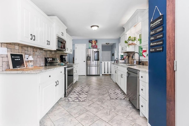 3006 S 39th St, Kansas City, KS 66106 - kitchen with stainless steel appliances, decorative backsplash, white cabinetry, and light stone countertops