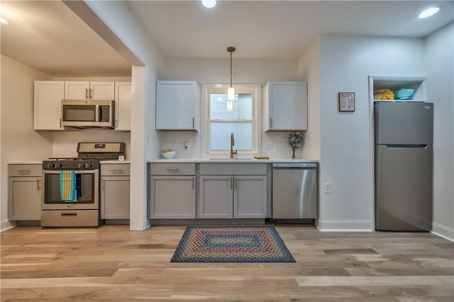 2606 Smart Ave, Kansas City, MO 64124 - kitchen with appliances with stainless steel finishes, light wood-style floors, gray cabinetry, decorative light fixtures, and recessed lighting