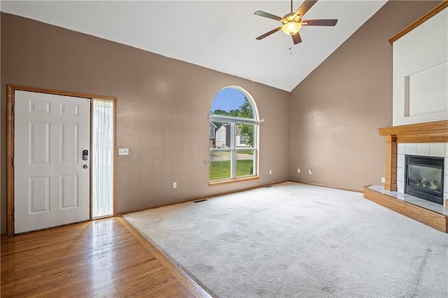 913 N Cochise Ave, Independence, MO 64056 - unfurnished living room with high vaulted ceiling, ceiling fan, a fireplace, wood finished floors, and carpet floors