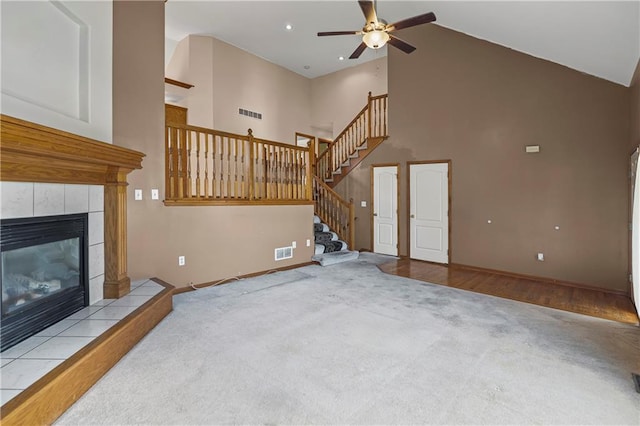 913 N Cochise Ave, Independence, MO 64056 - unfurnished living room featuring high vaulted ceiling, carpet floors, ceiling fan, a tile fireplace, and stairs