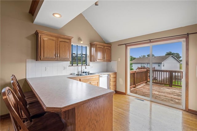 913 N Cochise Ave, Independence, MO 64056 - kitchen with stainless steel dishwasher, a kitchen breakfast bar, light wood-style floors, decorative backsplash, and a peninsula