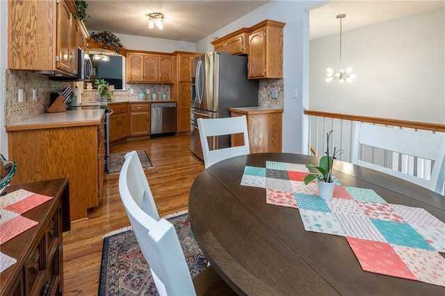 207 Woodhaven Dr, Smithville, MO 64089 - kitchen featuring stainless steel appliances, light wood finished floors, a chandelier, and tasteful backsplash
