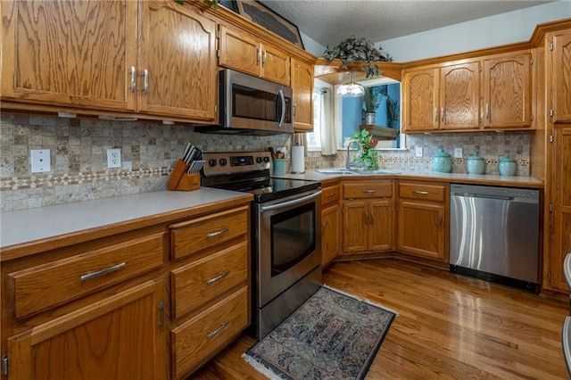 207 Woodhaven Dr, Smithville, MO 64089 - kitchen with stainless steel appliances, brown cabinetry, light countertops, decorative backsplash, and a textured ceiling