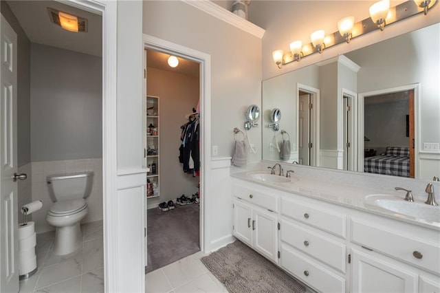 207 Woodhaven Dr, Smithville, MO 64089 - bathroom with double vanity, a wainscoted wall, a spacious closet, and tile patterned flooring