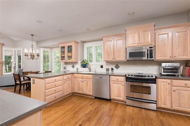 14333 Norwood St, Leawood, KS 66224 - kitchen with appliances with stainless steel finishes, light brown cabinets, a chandelier, decorative backsplash, and a peninsula
