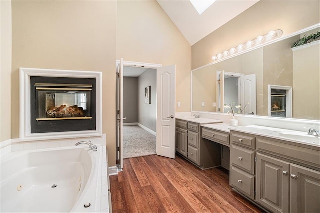 5713 NE Sapphire Ct, Lees Summit, MO 64064 - full bathroom featuring double vanity, high vaulted ceiling, a whirlpool tub, and wood finished floors