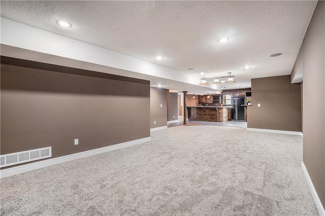 5713 NE Sapphire Ct, Lees Summit, MO 64064 - unfurnished living room with a textured ceiling, carpet floors, bar area, and recessed lighting