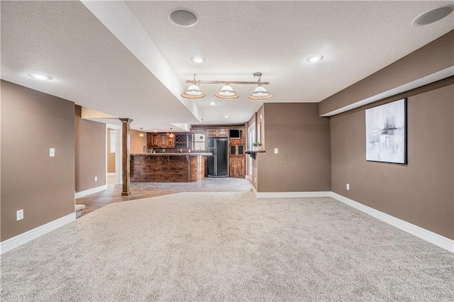 5713 NE Sapphire Ct, Lees Summit, MO 64064 - unfurnished living room featuring light carpet, a textured ceiling, bar, recessed lighting, and ornate columns