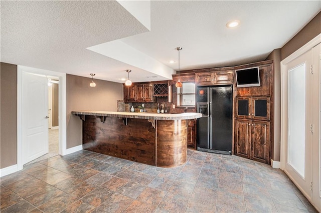 5713 NE Sapphire Ct, Lees Summit, MO 64064 - kitchen with black fridge with ice dispenser, a peninsula, a kitchen breakfast bar, light countertops, and hanging light fixtures