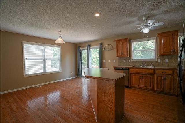 17586 W 161st St, Olathe, KS 66062 - kitchen featuring dishwasher, a textured ceiling, brown cabinets, wood finished floors, and a center island