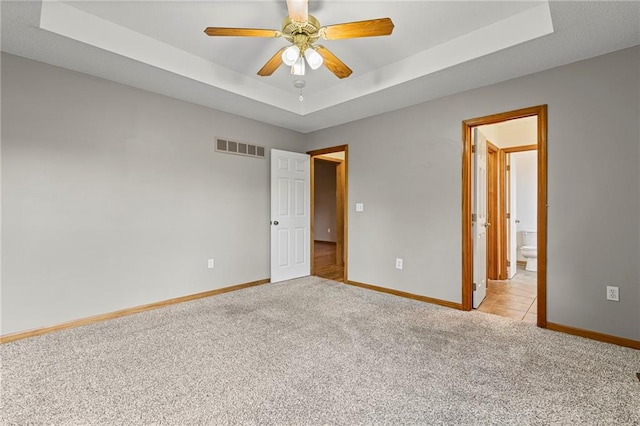 12324 S Clinton St, Olathe, KS 66061 - unfurnished bedroom featuring light colored carpet, a raised ceiling, ensuite bath, and a ceiling fan