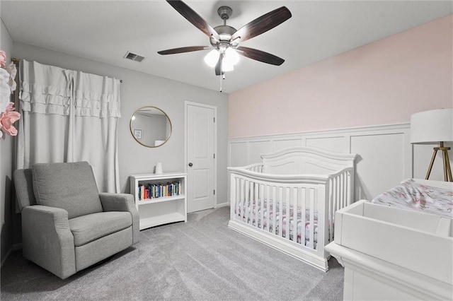 2312 SW Morris Dr, Lees Summit, MO 64082 - carpeted bedroom featuring a crib, wainscoting, and ceiling fan
