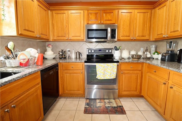 329 W 26th Ln, Eudora, KS 66025 - kitchen featuring appliances with stainless steel finishes, light tile patterned flooring, backsplash, and brown cabinetry