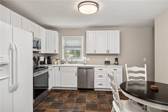 1304 S 39th St, Saint Joseph, MO 64507 - kitchen with appliances with stainless steel finishes, light countertops, dark stone finish flooring, and white cabinets