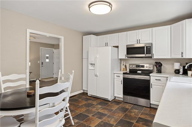 1304 S 39th St, Saint Joseph, MO 64507 - kitchen featuring stainless steel appliances, light countertops, dark stone finish floors, and white cabinetry