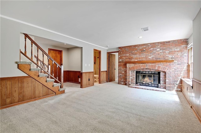 12303 W 105th Ter, Overland Park, KS 66215 - unfurnished living room featuring wainscoting, carpet, wood walls, stairway, and a brick fireplace