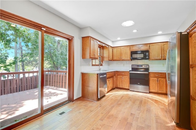 12303 W 105th Ter, Overland Park, KS 66215 - kitchen featuring appliances with stainless steel finishes, light wood finished floors, light countertops, tasteful backsplash, and brown cabinets