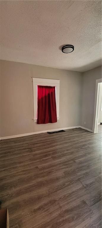 5107 E 26th St, Kansas City, MO 64127 - unfurnished room featuring dark wood finished floors and a textured ceiling