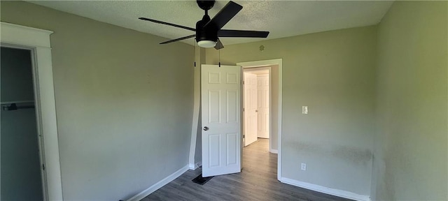 5107 E 26th St, Kansas City, MO 64127 - unfurnished bedroom with dark wood-style flooring, a textured ceiling, and a ceiling fan