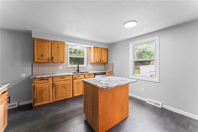 26 Misty Springs Cir, Platte City, MO 64079 - kitchen featuring backsplash, stainless steel dishwasher, a textured ceiling, a center island, and brown cabinets