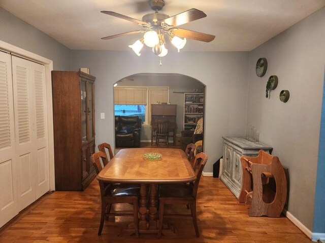 520 S Russell St, Odessa, MO 64076 - dining area featuring arched walkways, ceiling fan, and wood finished floors