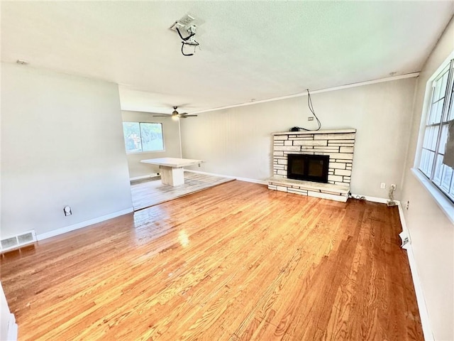 1012 NW A St, Blue Springs, MO 64015 - unfurnished living room with a stone fireplace, ceiling fan, and wood finished floors
