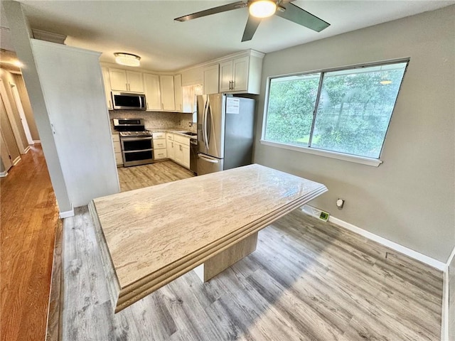 1012 NW A St, Blue Springs, MO 64015 - kitchen with stainless steel appliances, a ceiling fan, light wood finished floors, and white cabinets