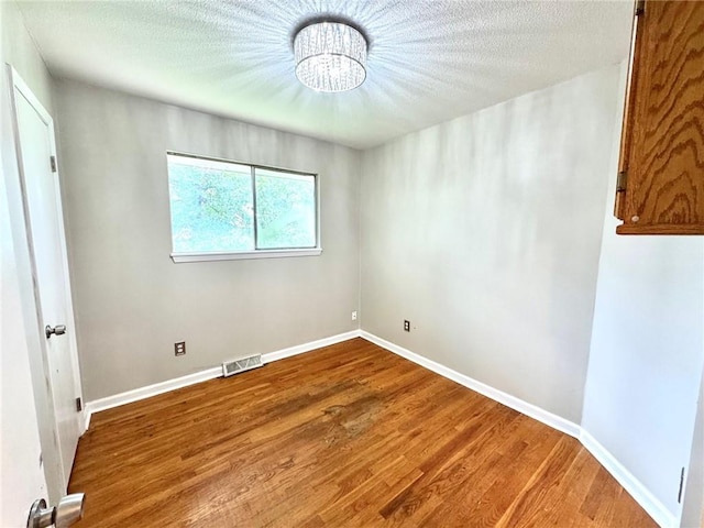 1012 NW A St, Blue Springs, MO 64015 - unfurnished room with a chandelier, wood finished floors, and a textured ceiling