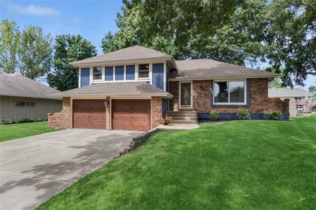 604 SE Richardson Pl, Lees Summit, MO 64063 - split level home with driveway, a front lawn, a garage, and brick siding