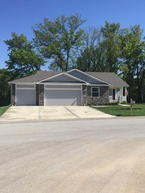 19706 E 20th St N, Independence, MO 64058 - view of front of house with stone siding, an attached garage, concrete driveway, and a front lawn