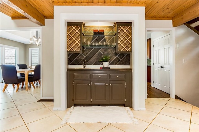 5490 W 85th Ter, Prairie Village, KS 66207 - wine area with light tile patterned floors, wet bar, a wooden ceiling with exposed beams, and a chandelier