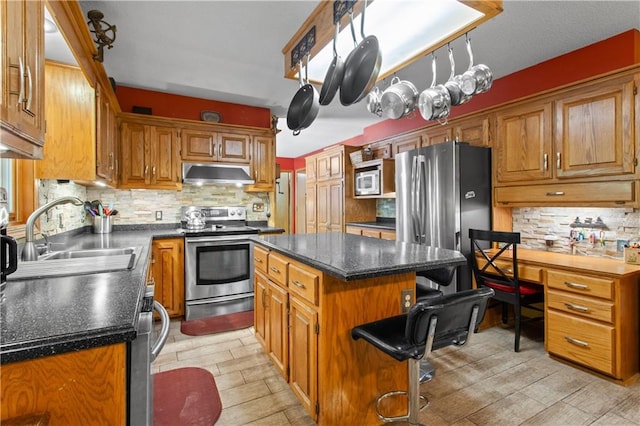 1684 Quarry Rd, Bates City, MO 64011 - kitchen featuring appliances with stainless steel finishes, under cabinet range hood, backsplash, dark countertops, and a kitchen bar