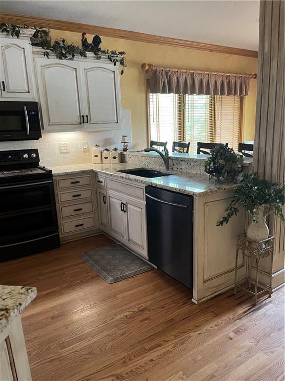 15733 Pine Cir, Basehor, KS 66007 - kitchen featuring dishwashing machine, electric range, a peninsula, light wood-style floors, and light stone counters