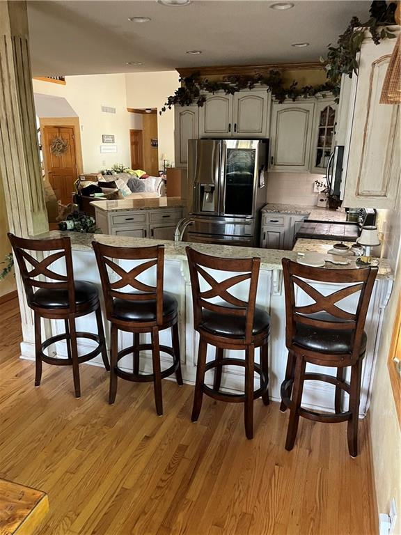15733 Pine Cir, Basehor, KS 66007 - kitchen with stainless steel appliances, a peninsula, light wood-type flooring, and light countertops