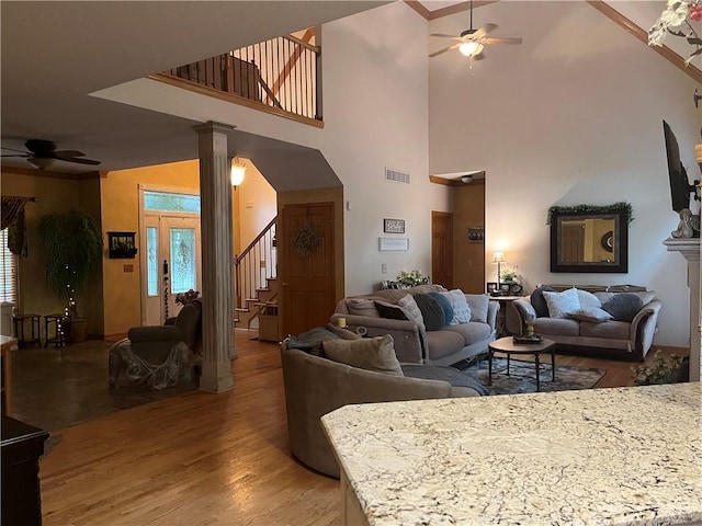 15733 Pine Cir, Basehor, KS 66007 - living room featuring a ceiling fan, light wood-style flooring, stairs, a high ceiling, and decorative columns