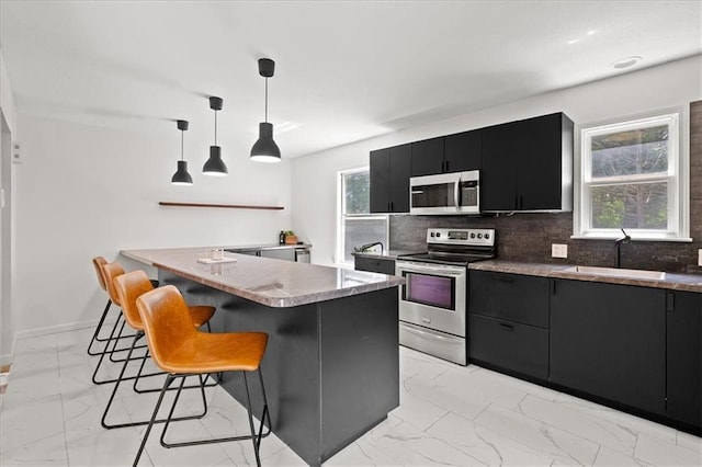 9410 Taylor Dr, Overland Park, KS 66212 - kitchen with dark cabinets, appliances with stainless steel finishes, light marble finish flooring, a kitchen bar, and tasteful backsplash