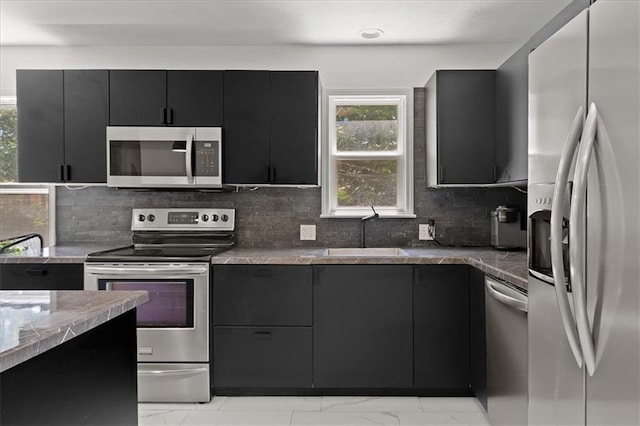9410 Taylor Dr, Overland Park, KS 66212 - kitchen with stainless steel appliances, dark cabinets, light marble finish flooring, tasteful backsplash, and stone countertops