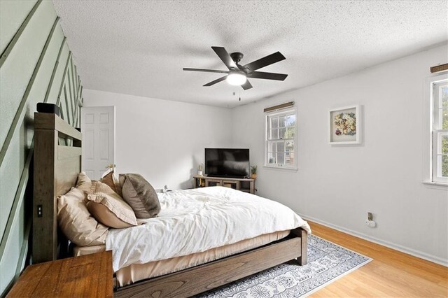 9410 Taylor Dr, Overland Park, KS 66212 - bedroom featuring multiple windows, wood finished floors, a textured ceiling, and a ceiling fan
