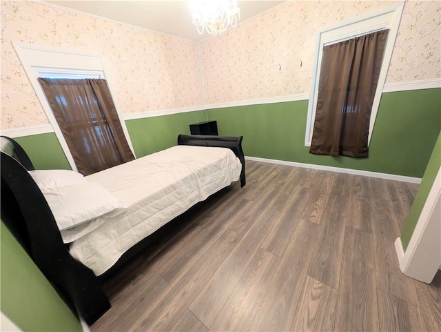 712 N Jefferson Ave, Iola, KS 66749 - bedroom with wallpapered walls, wood finished floors, wainscoting, and a chandelier