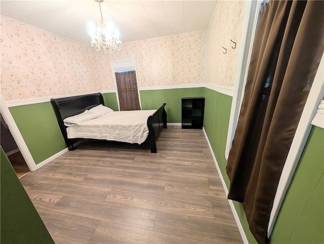712 N Jefferson Ave, Iola, KS 66749 - bedroom featuring wainscoting, wallpapered walls, wood finished floors, and a chandelier